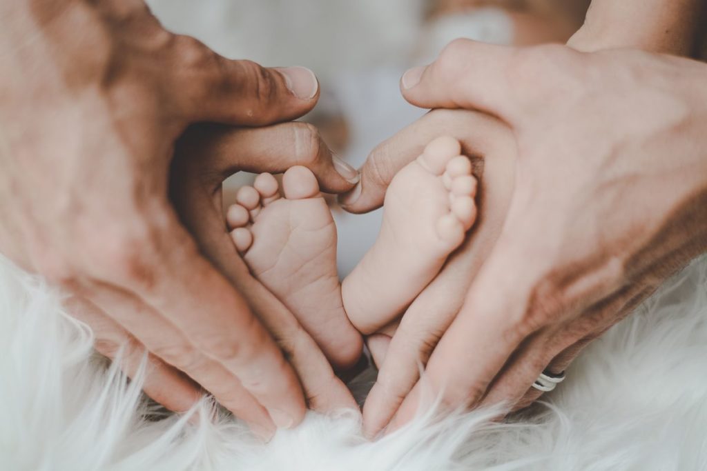 父母用手比愛心包著嬰兒的雙腳